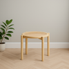Wooden stool with woven seat in a minimalistic room with a plant.