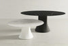 Two round tables, one white and one black, on a light gray background