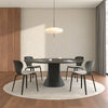 Modern dining room with a round black table and chairs on a wooden floor.