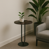 Small round marble table with a plant next to a gray armchair in a room.