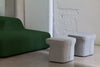 Green sofa with two gray stools against a white brick wall.
