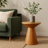 Wooden side table with a plant next to a green sofa in a living room setting.