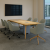 Conference room with a wooden table and gray chairs, featuring a television on the wall.