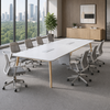 Modern conference room with a large white table and gray chairs, featuring a cityscape view through large windows.